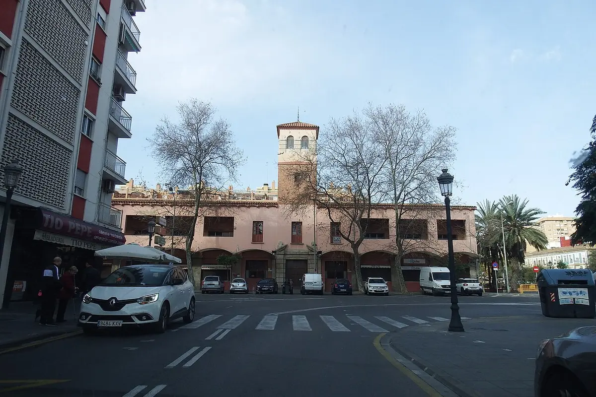 The Cabanyal Municipal Market in Valencia, a low pink building with a small tower, seen across a street with plane trees